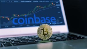 Un Bitcoin reposa sobre una computadora con el logotipo de Coinbase (COIN) y un gráfico de operaciones.