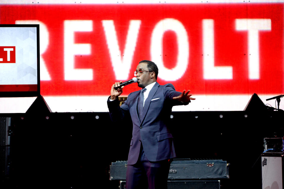 Combs habla a través de un micrófono frente a un fondo con el logo de Revolt.