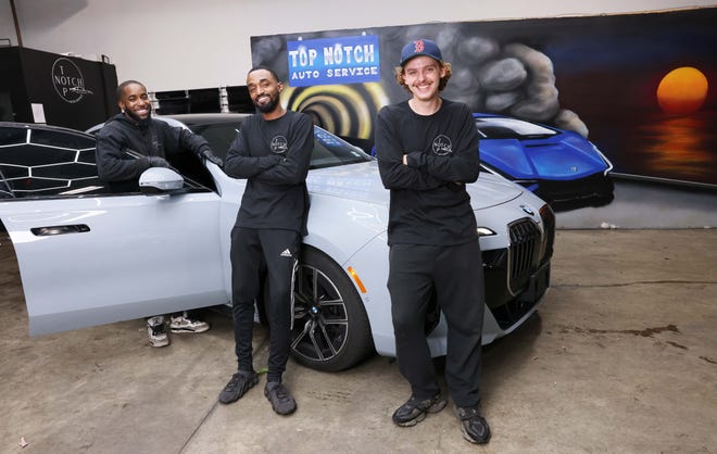 De izquierda a derecha, Jevaughn Evans, AJ Jaramillo y Jimbo Babb muestran uno de los vehículos en Top Notch Auto Service, el negocio de detallado de automóviles y tintado de ventanas de Jaramillo en East Bridgewater, el jueves 19 de septiembre de 2024.