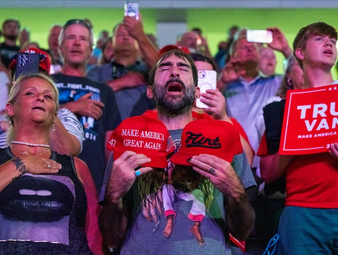 La gente permanece de pie durante el Himno Nacional antes de que el expresidente Donald Trump hable ante una audiencia durante una reunión municipal en el Dort Financial Center en Flint, Michigan, el martes 17 de septiembre de 2024.