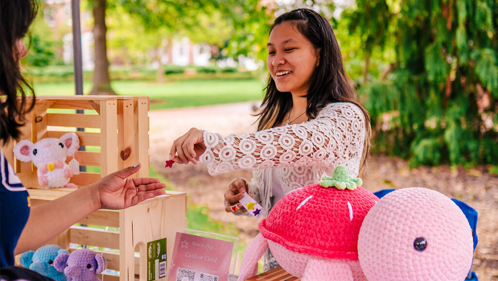 Un estudiante emprendedor de la UNCG le regala una joya a un cliente.