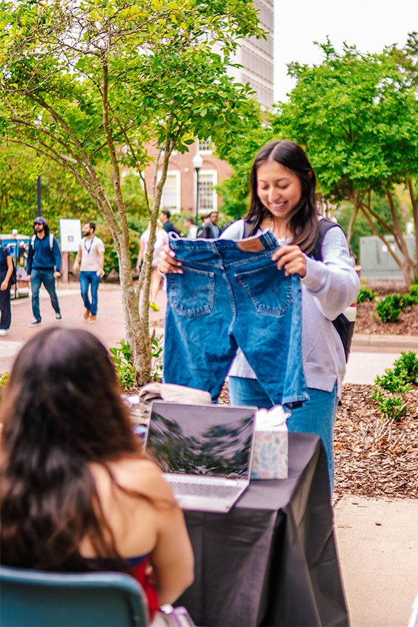 Un estudiante de la UNCG mira un par de pantalones cortos de jean que se venden en el mercado estudiantil.