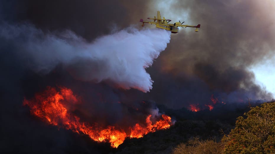 PACIFIC PALISADES, CALIF 7 DE ENERO DE 2024 Un avión de extinción de incendios cae sobre el incendio de Palisades en Pacific Palisades el martes 7 de enero. El incendio de Palisades está siendo empujado por ráfagas de viento de Santa Ana que se esperaba que continuaran durante dos días más. (Brian van der Brug/Los Angeles Times vía Getty Images)