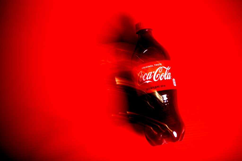 Una botella de Coca-Cola sobre fondo rojo.