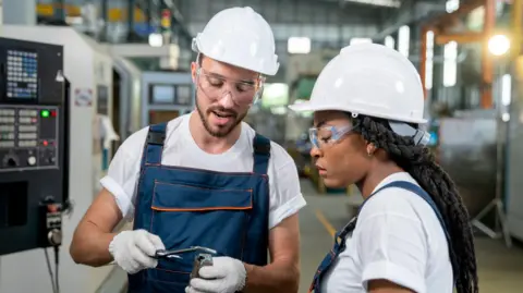 Getty Images Dos ingenieros con cascos blancos mirando un equipo